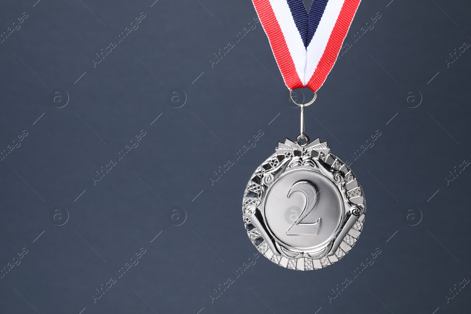 Photo of Silver medal with striped ribbon on grey background, space for text