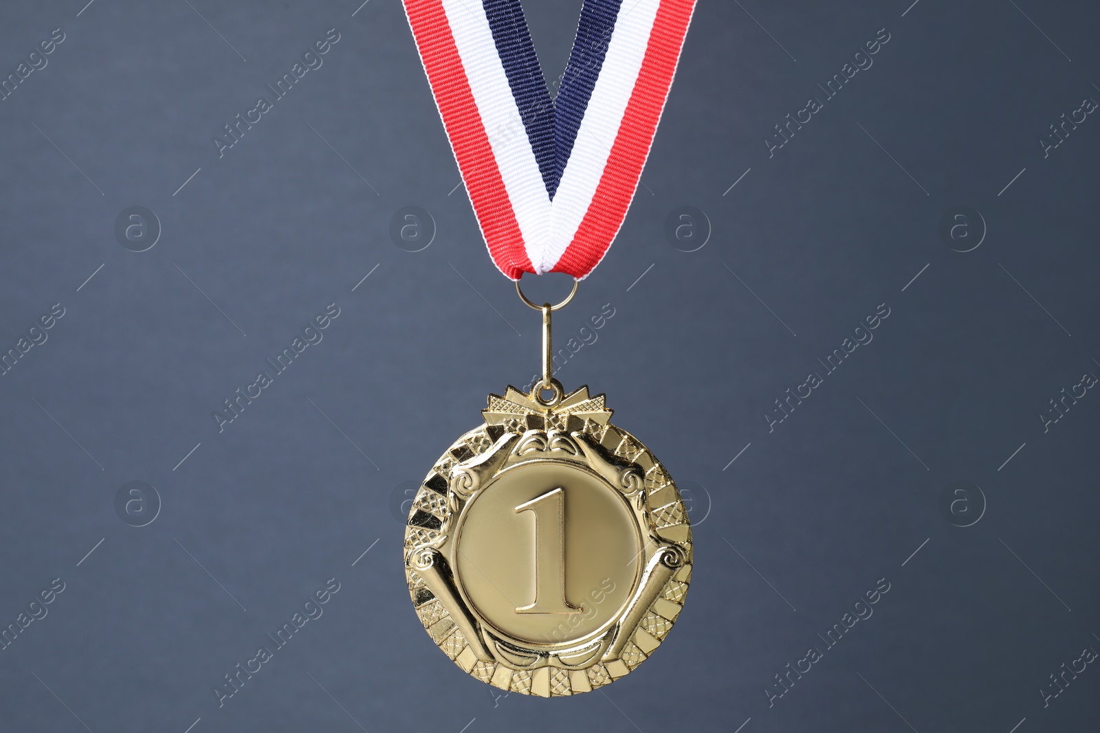 Photo of Golden medal with striped ribbon on grey background