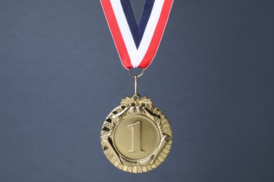 Photo of Golden medal with striped ribbon on grey background