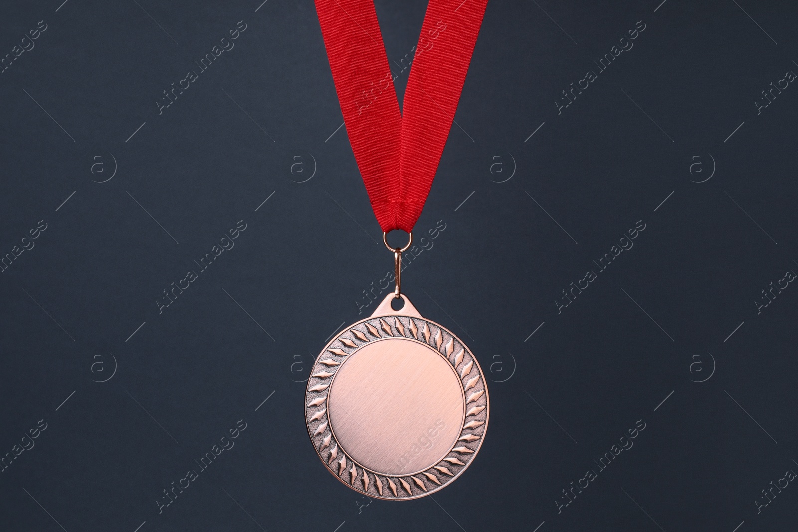 Photo of Bronze medal with red ribbon on dark grey background