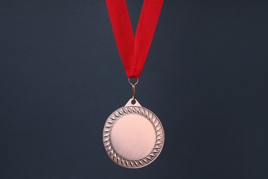 Photo of Bronze medal with red ribbon on dark grey background