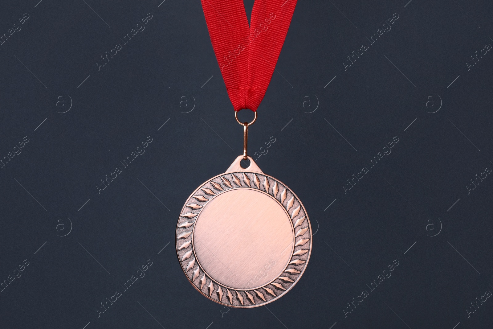 Photo of Bronze medal with red ribbon on dark grey background