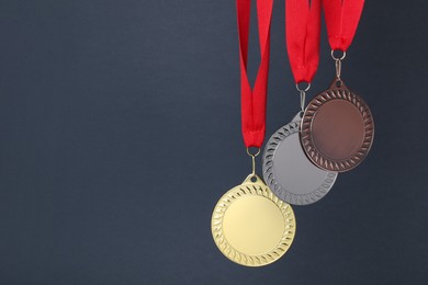 Photo of Golden, silver and bronze medals on dark grey background, space for text