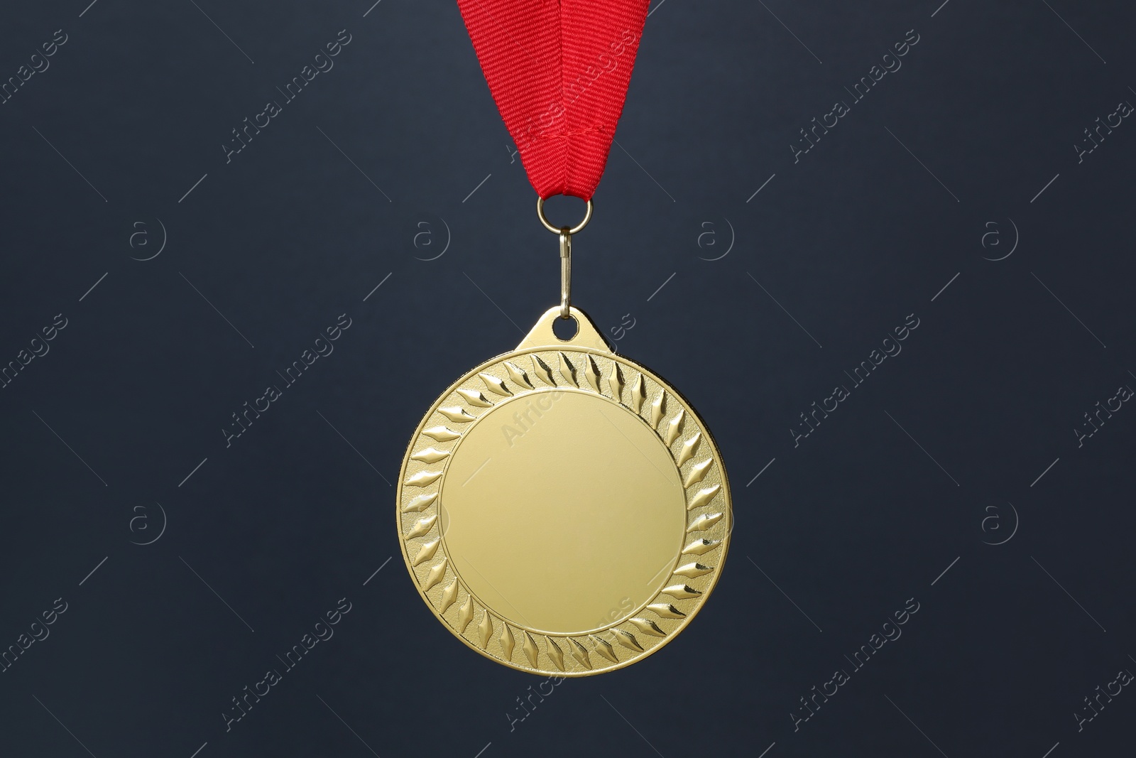 Photo of Golden medal with red ribbon on dark grey background