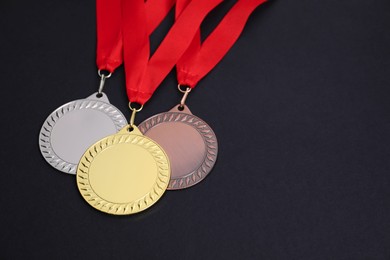 Photo of Golden, silver and bronze medals on black background, closeup. Space for text