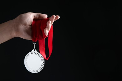 Photo of Woman with silver medal on black background, closeup. Space for text