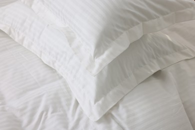 Photo of Bed with clean linens and pillows at home, closeup