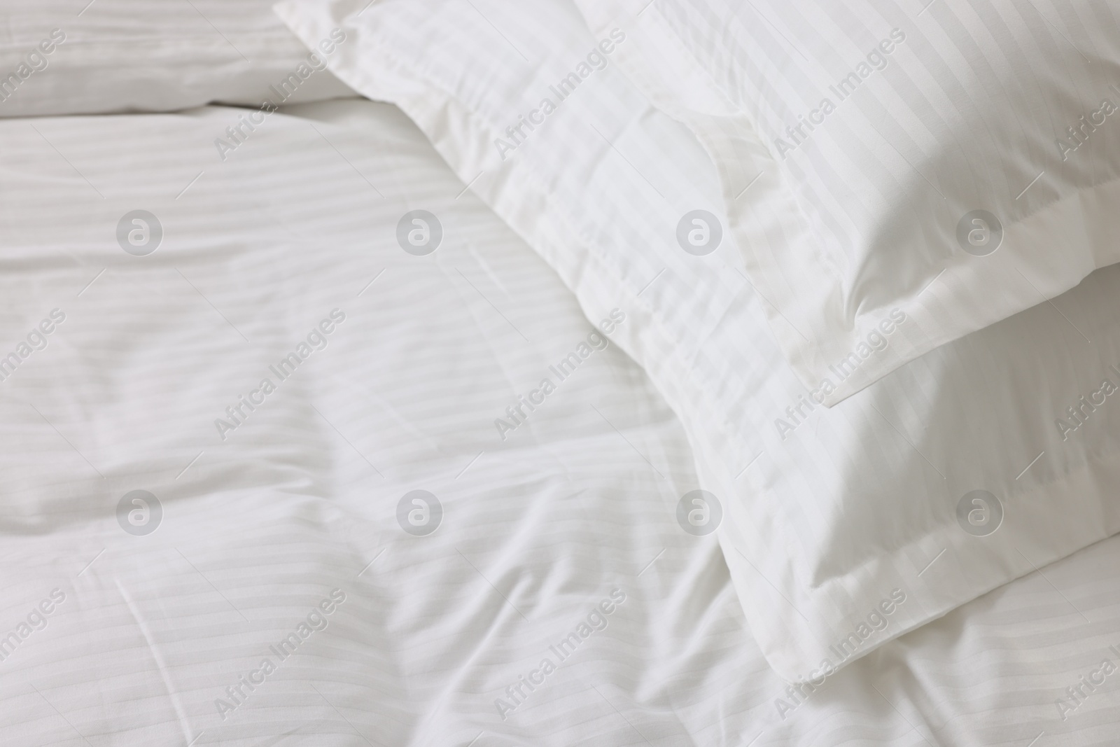 Photo of Bed with clean linens and pillows at home, closeup. Space for text