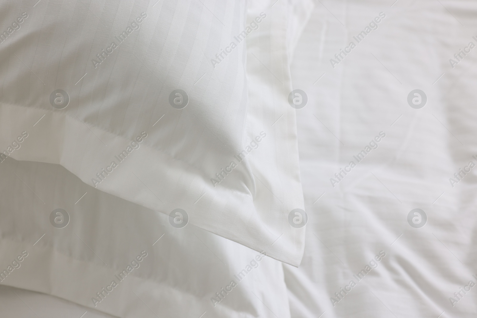 Photo of Bed with clean linens and pillows at home, closeup