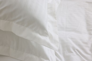 Bed with clean linens and pillows at home, closeup