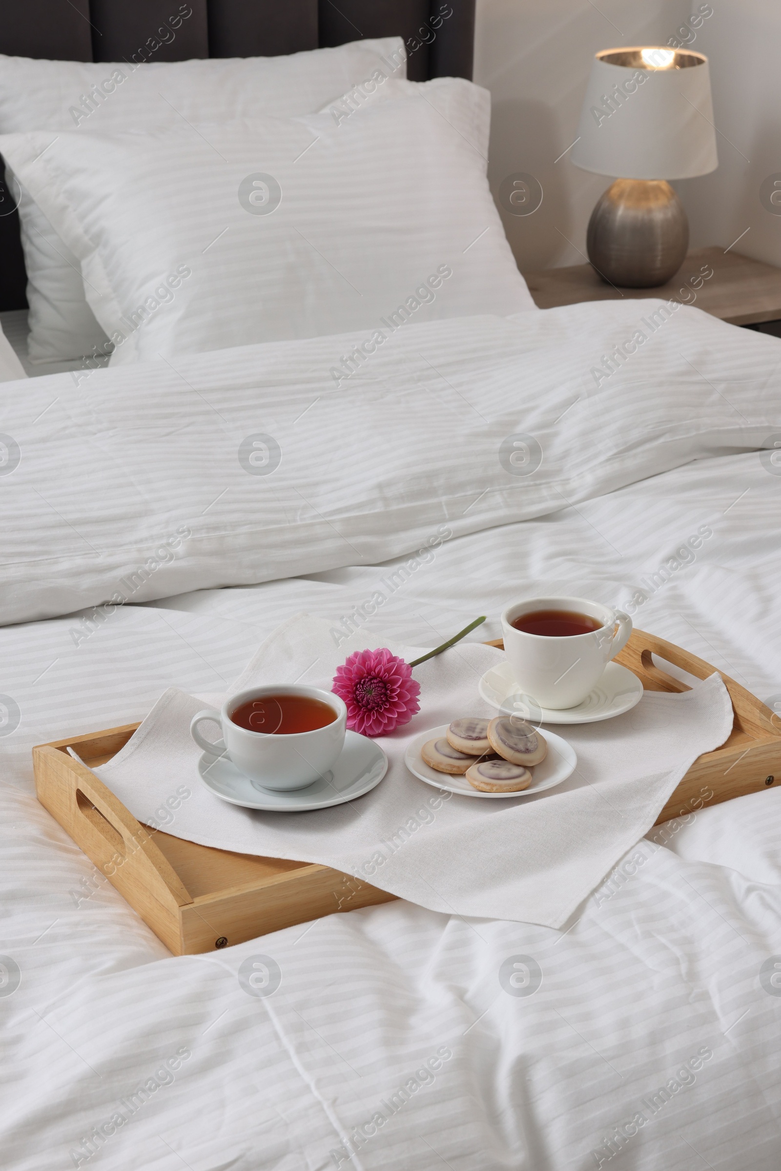 Photo of Breakfast tray on bed with beautiful linens indoors