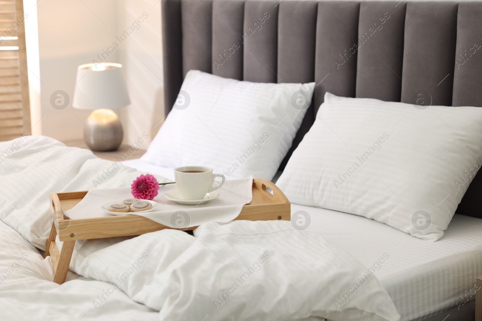 Photo of Breakfast tray on bed with beautiful linens indoors