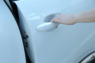 Photo of Woman opening door of white car outdoors, closeup