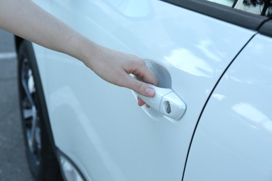 Woman opening door of white car outdoors, closeup