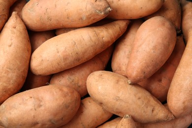 Photo of Fresh raw sweet potatoes as background, top view