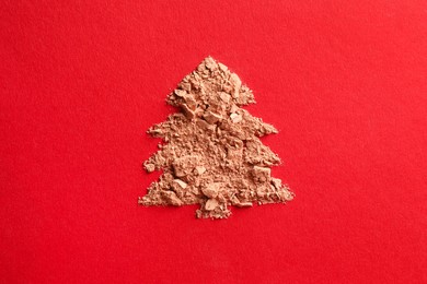 Christmas tree made of face powder on red background, top view