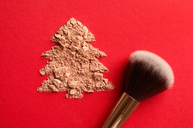 Photo of Christmas tree made of face powder and brush on red background, top view