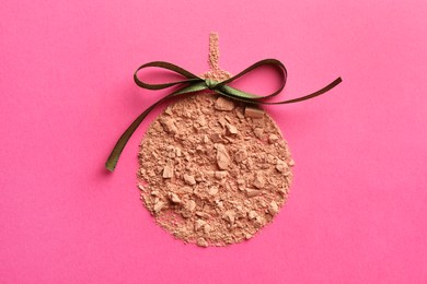 Photo of Christmas ball made with face powder on pink background, top view