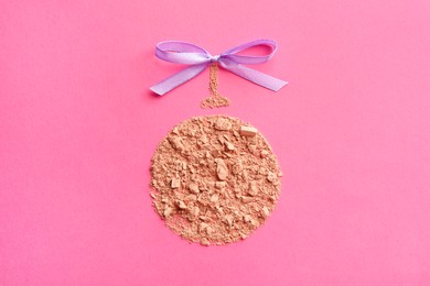 Christmas ball made with face powder on pink background, top view