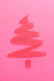 Christmas tree drawn with lipstick on pink background, top view