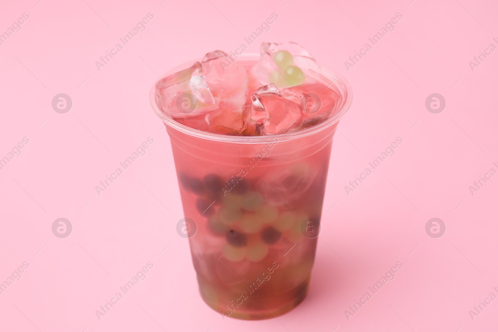 Photo of Tasty bubble tea in plastic cup on pink background