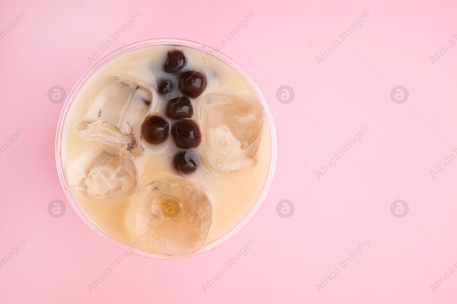 Photo of Tasty milk bubble tea in plastic cup on pink background, top view. Space for text