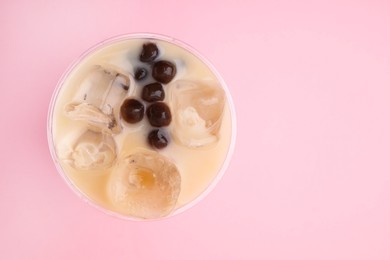 Photo of Tasty milk bubble tea in plastic cup on pink background, top view. Space for text