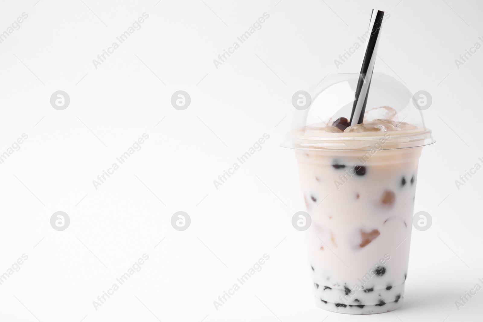 Photo of Tasty milk bubble tea in plastic cup on white background, space for text