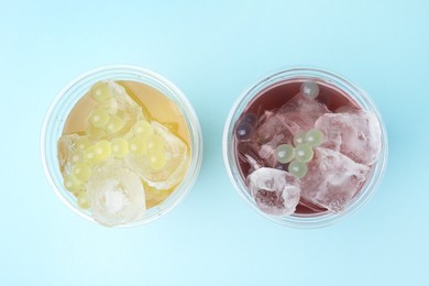 Tasty bubble tea in plastic cups on light blue background, flat lay