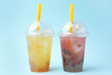 Tasty bubble tea in plastic cups on light blue background