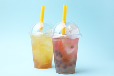 Tasty bubble tea in plastic cups on light blue background