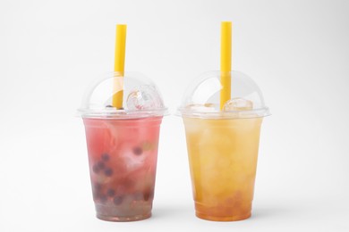 Tasty bubble tea in plastic cups on white background