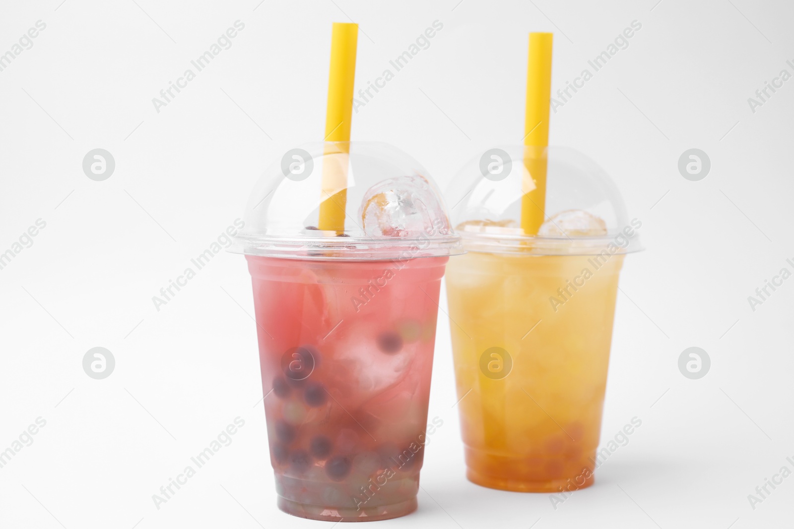 Photo of Tasty bubble tea in plastic cups on white background