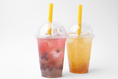 Tasty bubble tea in plastic cups on white background