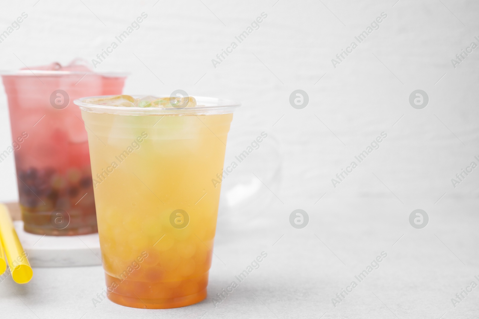 Photo of Tasty bubble tea in plastic cups on light table, space for text