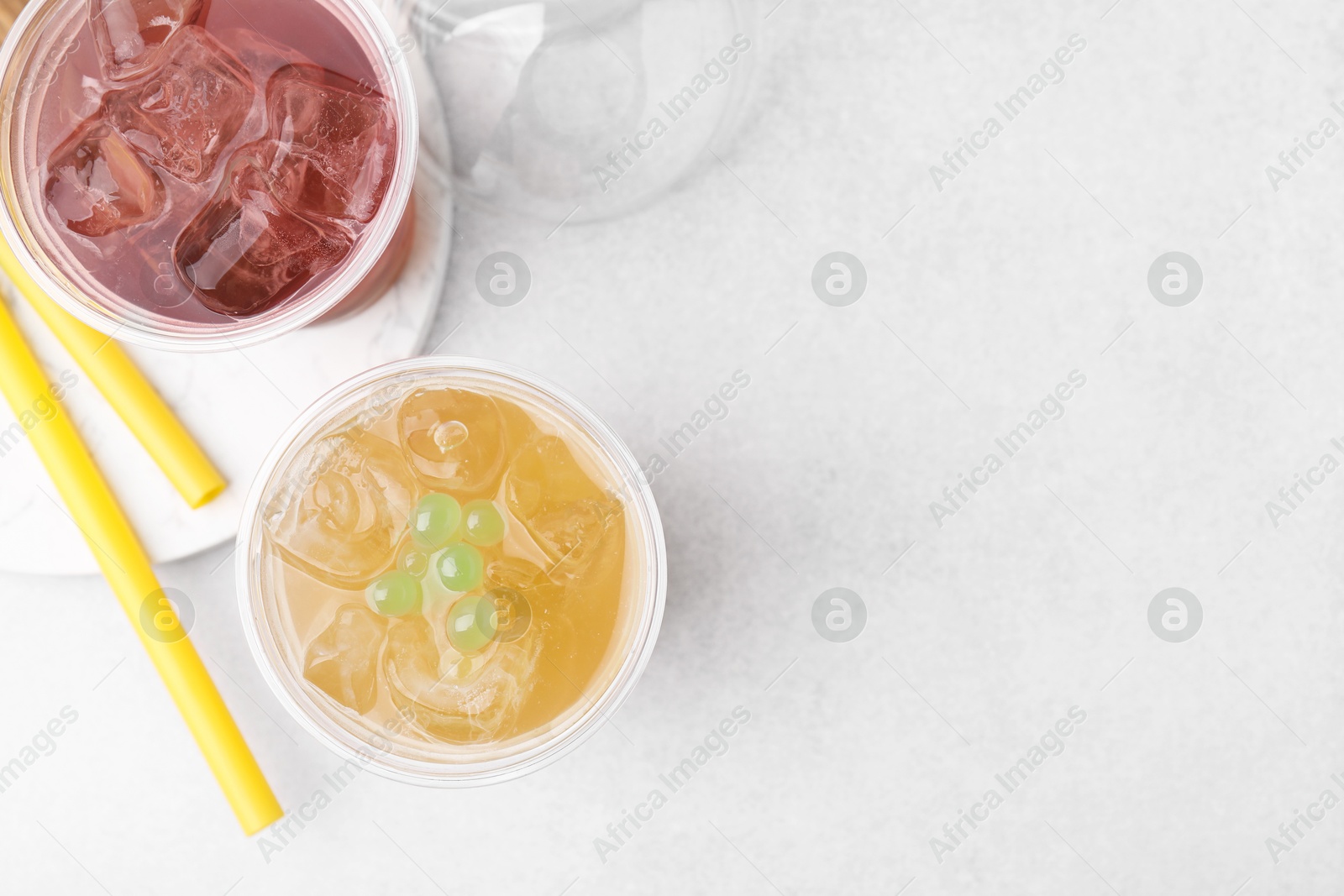 Photo of Tasty bubble tea in plastic cups and straws on light table, flat lay. Space for text