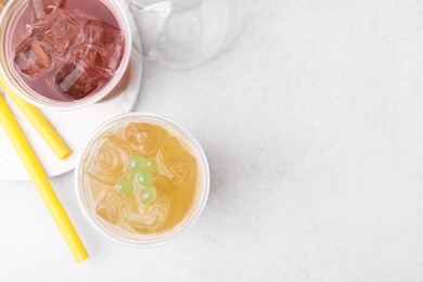 Photo of Tasty bubble tea in plastic cups and straws on light table, flat lay. Space for text