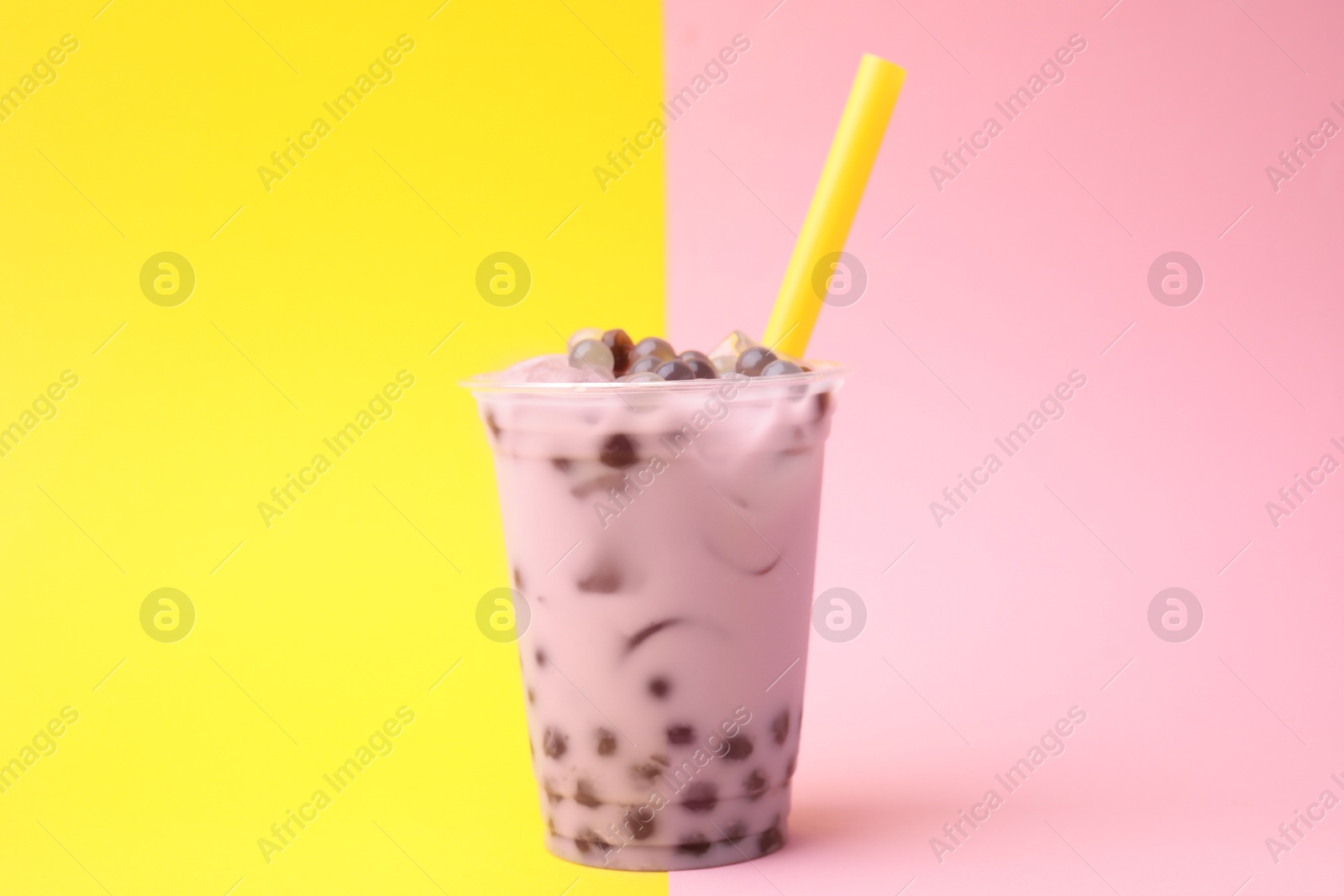 Photo of Tasty milk bubble tea in plastic cup on color background