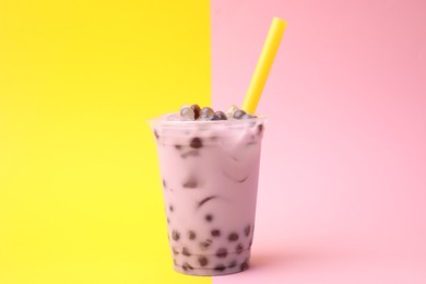 Tasty milk bubble tea in plastic cup on color background