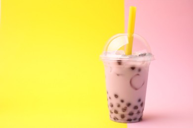 Tasty milk bubble tea in plastic cup on color background, space for text