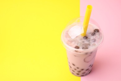 Photo of Tasty milk bubble tea in plastic cup on color background, space for text