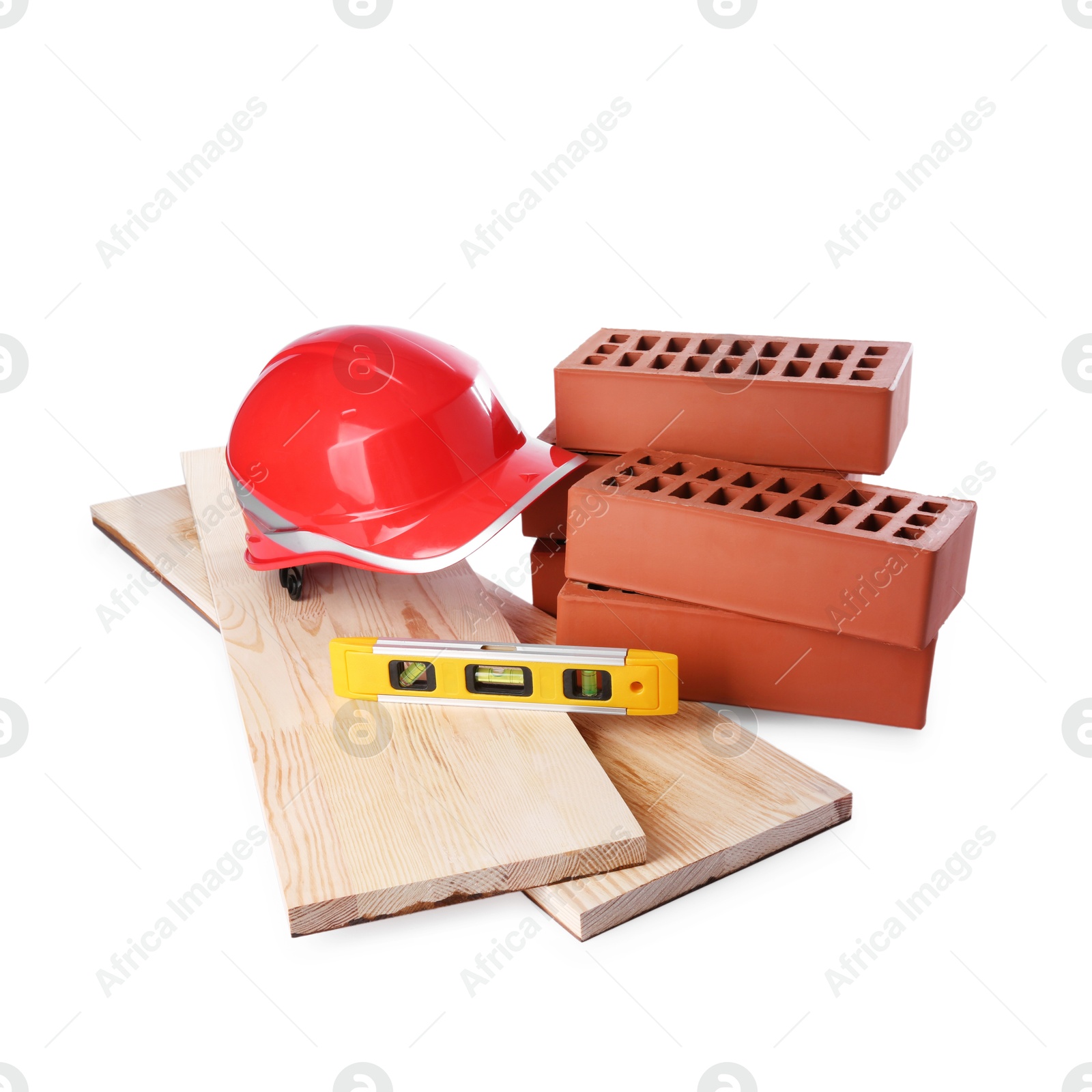 Photo of Wooden planks, orange hard hat, building level and red bricks isolated on white. Construction tools