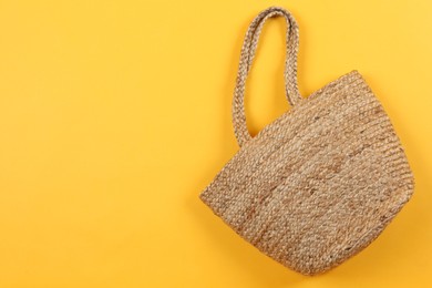 Photo of Stylish woman's straw bag on yellow background, top view. Space for text