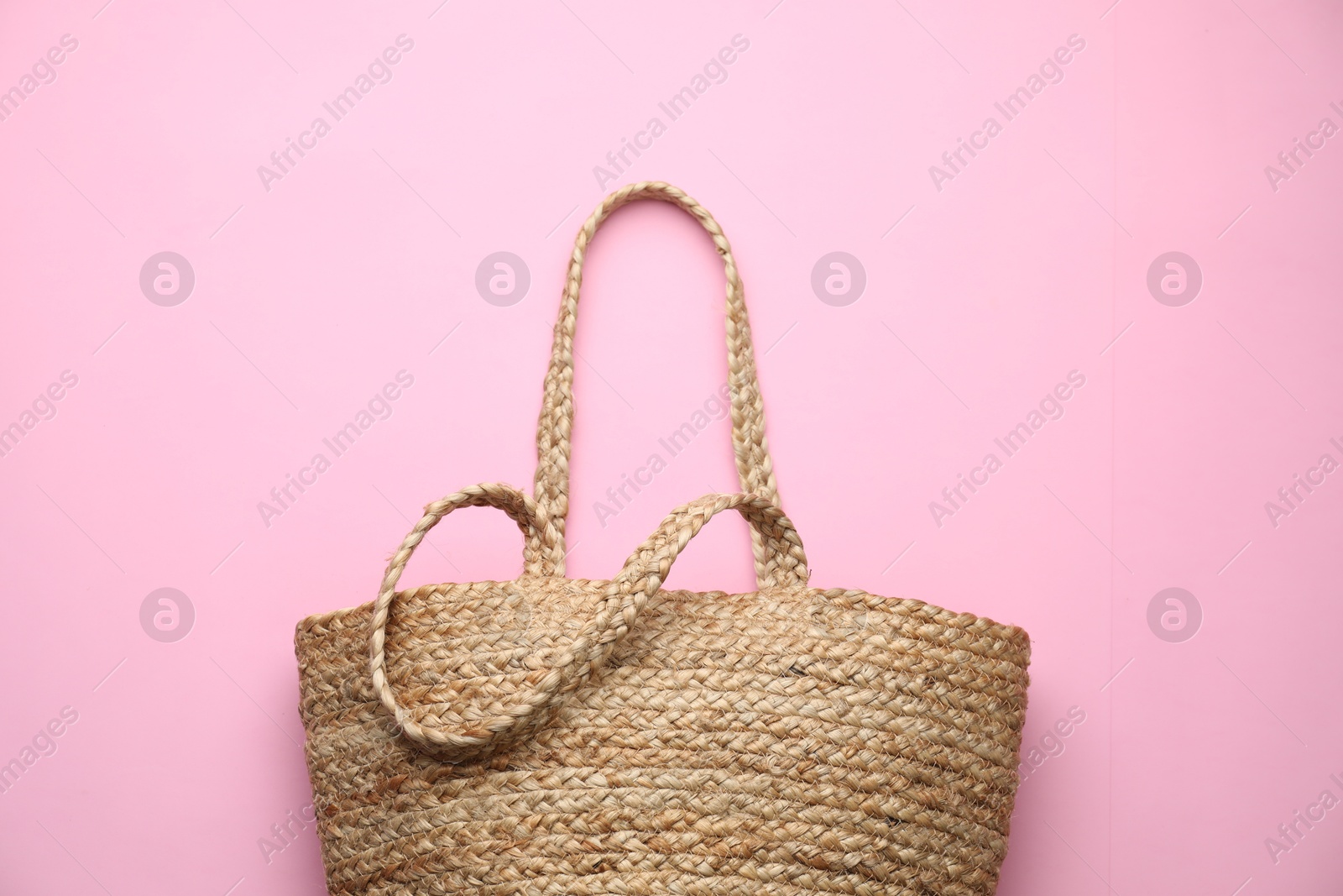 Photo of Elegant woman's straw bag on pink background, top view