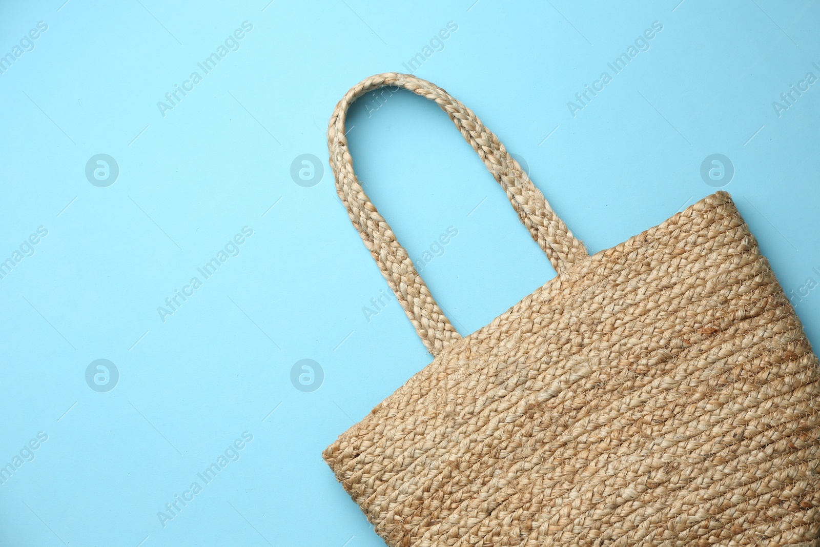 Photo of Elegant woman's straw bag on light blue background, top view. Space for text