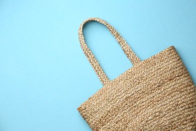 Photo of Elegant woman's straw bag on light blue background, top view. Space for text