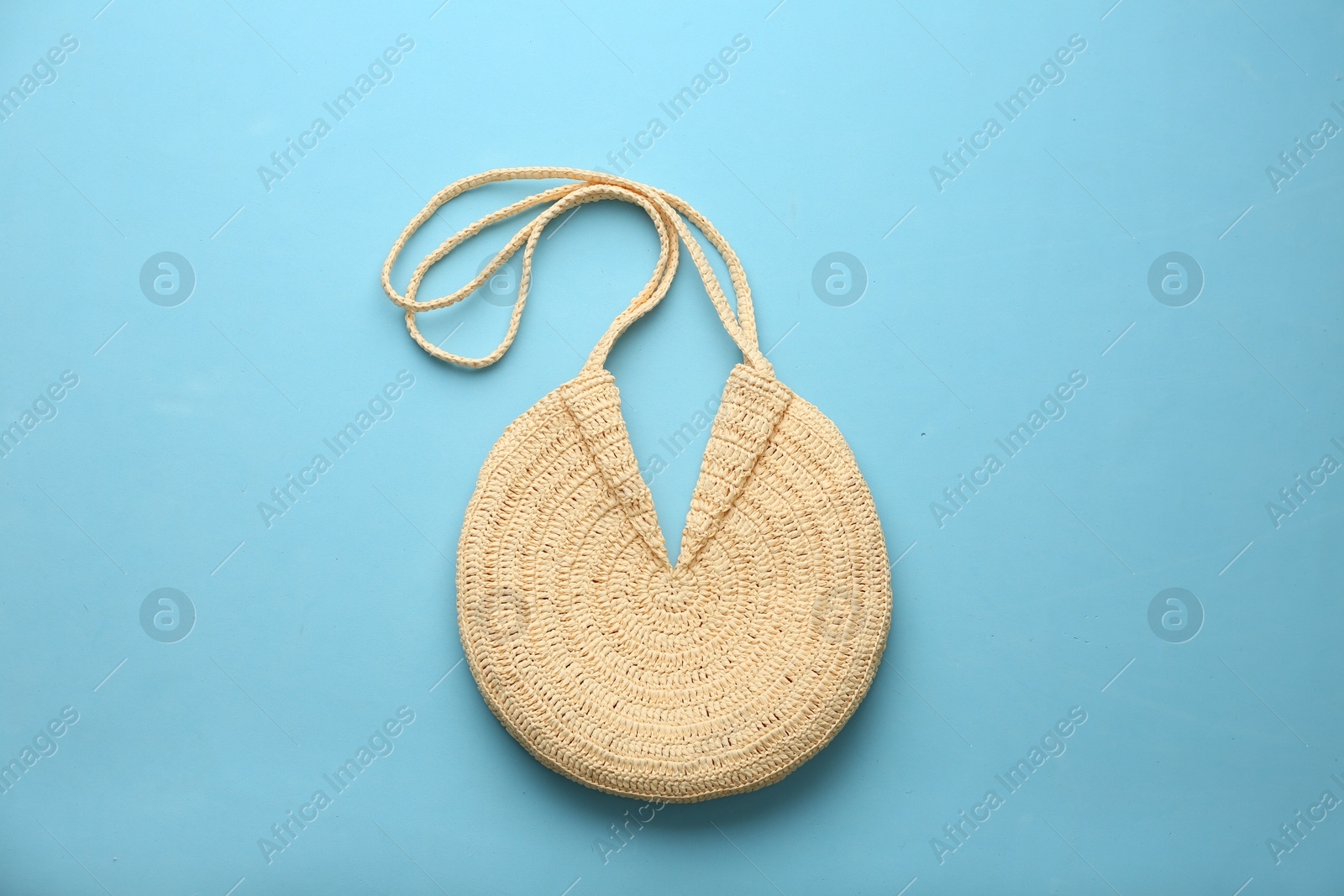 Photo of Elegant woman's straw bag on light blue background, top view