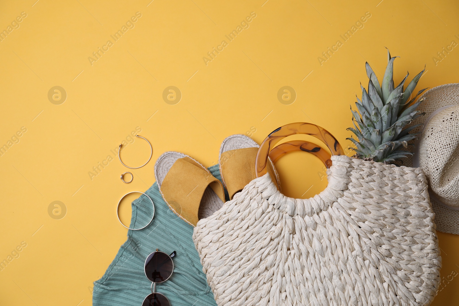 Photo of Stylish straw bag and summer accessories on yellow background, flat lay. Space for text