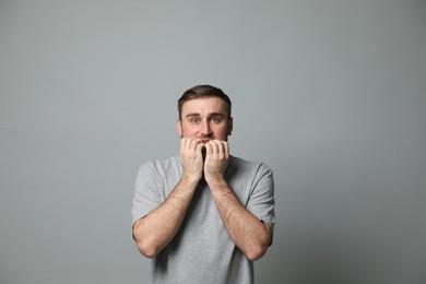 Young man feeling fear on grey background