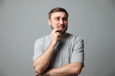 Young man feeling fear on grey background